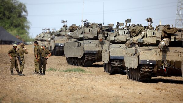 Israeli soldiers speak next to a tank as military armoured vehicles gather in an open area near Israel's border with the Gaza Strip - Sputnik Afrique