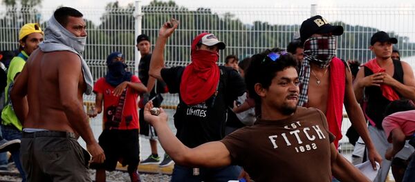A man part of a caravan of thousands of migrants from Central America en route to the U.S, throws a stone to the Mexican Police as they try to pull down the border gate with the intention to carry on their journey, in Tecun Uman, Guatemala, October 28, 2018. - Sputnik Afrique