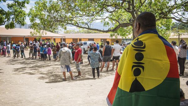 A man drapes his country's flag over his shoulders as residents of New Caledonia's capital, Noumea, wait in line at a polling station before casting their vote as part of an independence referendum, Sunday, Nov. 4, 2018. - Sputnik Afrique