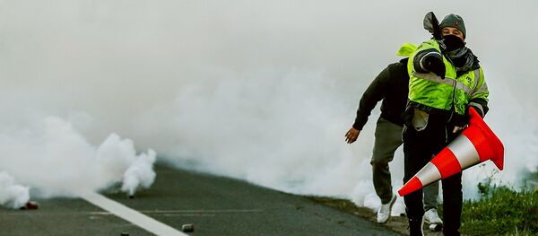 A man throws a projectile on Caen's circular road on November 18, 2018 in Caen, northwestern France, on a second day of action after a nationwide popular initiated day of protest called yellow vest (Gilets Jaunes in French) movement against high fuel prices which has mushroomed into a widespread protest against stagnant spending power under French President. - Sputnik Afrique