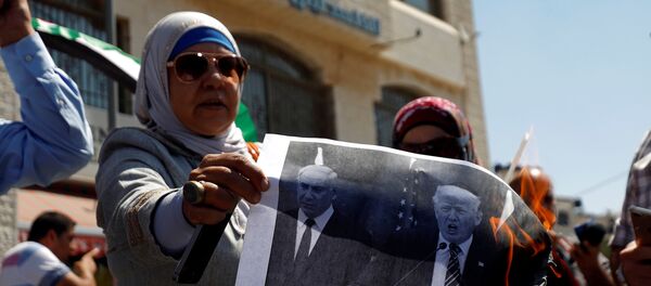 A Palestinian woman burns a picture of U.S. President Donald Trump and Israeli Prime Minister Benjamin Netanyahu during a protest against a U.S. decision to cut funding to the United Nations Relief and Works Agency (UNRWA), in Ramallah, in the occupied West Bank September 4, 2018.  - Sputnik Afrique