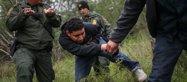 U.S. Border Patrol Agents help men from Central America pass through a barbed wire fence after they were apprehended for illegally crossing into the United States from Mexico in La Joya, Texas, U.S., October 17, 2018 - Sputnik Afrique