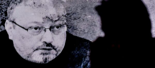 A man passes in front of a screen showing Jamal Khashoggi during a commemoration event of Khashoggi's supporters on November 11, 2018 in Istanbul - Sputnik Afrique