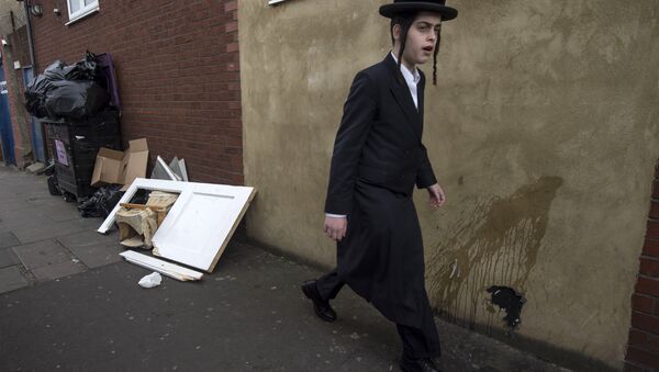An Orthodox jew walks past a damaged door belonging to the Ahavas Torah synagogue in the Stamford Hill area of north London on March 22, 2015 - Sputnik Afrique