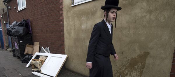 An Orthodox jew walks past a damaged door belonging to the Ahavas Torah synagogue in the Stamford Hill area of north London on March 22, 2015 - Sputnik Afrique