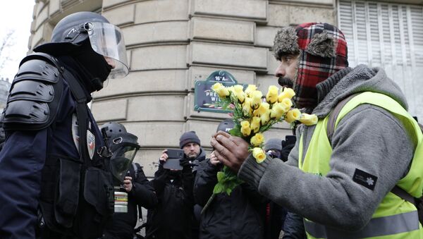 A demonstrator wearing his yellow vest holds a bouquet of roses in front of a riot police officer during a protest Saturday, Dec. 15, 2018 in Paris. - Sputnik Afrique