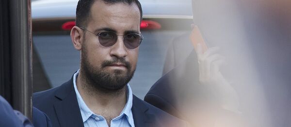A photo taken on July 16, 2018 shows Elysee senior security officer Alexandre Benalla standing next to a bus and the plane transporting the France's national football team at the Roissy-Charles de Gaulle airport - Sputnik Afrique