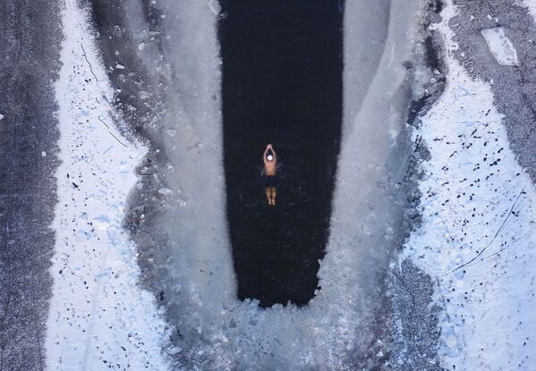 Un homme nage dans un lac partiellement pris de glaces à Shenyang, dans la province chinoise du Liaoning - Sputnik Afrique