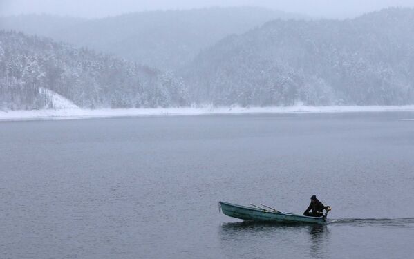 Un homme sur un bateau traverse sous la neige le fleuve Ienisseï près de Krasnoïarsk, en Russie - Sputnik Afrique