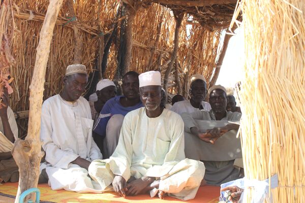 Des hommes assis dans un arbri en matériau provisoire au camp des déplacés de Igawa Mémé, Extrême-Nord, Cameroun Des hommes assis dans un arbri en matériau provisoire au camp des déplacés de Igawa Mémé, Extrême-Nord, Cameroun - Sputnik Afrique
