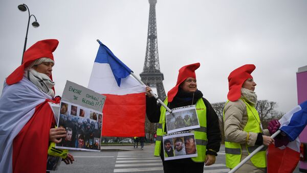 Women wearing yellow vests (gilets jaunes) hold pictures of protesters wounded by police forces in front of the Eiffel tower and a placard reading how many more wounded people?, in Paris, on January 20, 2019 - Sputnik Afrique
