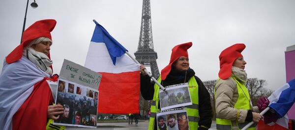 Women wearing yellow vests (gilets jaunes) hold pictures of protesters wounded by police forces in front of the Eiffel tower and a placard reading how many more wounded people?, in Paris, on January 20, 2019 - Sputnik Afrique