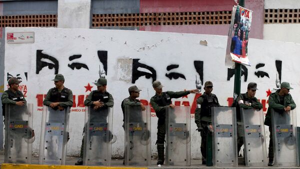 National Guard soldiers stand guard outside a polling station where a wall is covered with stencil paintings depicting the eyes of Venezuela's late President Hugo Chavez, during congressional elections in Caracas, Venezuela, Sunday, Dec. 6, 2015 - Sputnik Afrique