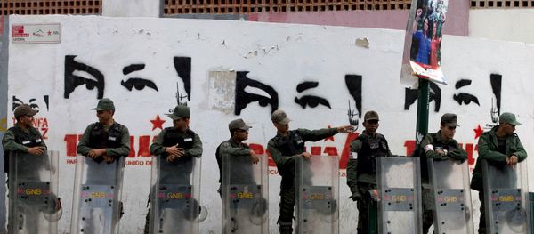 National Guard soldiers stand guard outside a polling station where a wall is covered with stencil paintings depicting the eyes of Venezuela's late President Hugo Chavez, during congressional elections in Caracas, Venezuela, Sunday, Dec. 6, 2015 National Guard soldiers stand guard outside a polling station where a wall is covered with stencil paintings depicting the eyes of Venezuela's late President Hugo Chavez, during congressional elections in Caracas, Venezuela, Sunday, Dec. 6, 2015 - Sputnik Afrique