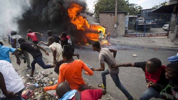 Demonstrators run away from police who are shooting in their direction, as a car burns during a protest demanding the resignation of Haitian President Jovenel Moise in Port-au-Prince, Haiti, Tuesday, Feb. 12, 2019. - Sputnik Afrique