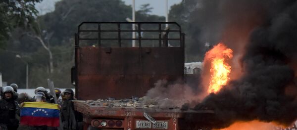 Venezuelan security forces display a national flag next to a truck which was burnt during the weekend when trying to enter the country with humanitarian aid, during clashes with supporters of Venezuelan opposition leader Juan Guaido on the Venezuelan side of the Francisco de Paula Santander International Bridge, as seen from Cucuta, Colombia, on February 25, 2019. - Sputnik Afrique