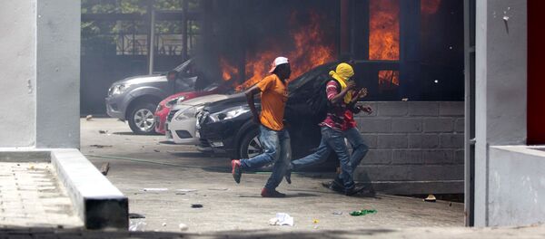 People run away after cars were set on fire at a Nissan dealership during protests over a fuel price increase in Port-au-Prince, Haiti, on Saturday, July 7, 2018 - Sputnik Afrique