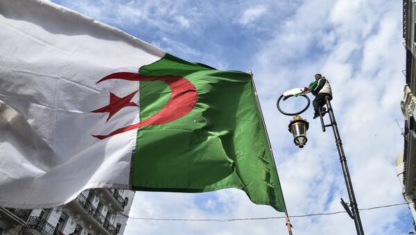 This picture taken on March 22, 2019 shows an Algerian national flag flying during a demonstration against ailing President Abdelaziz Bouteflika in the capital Algiers. - Sputnik Afrique