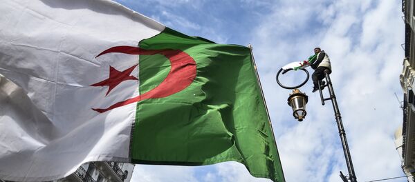 This picture taken on March 22, 2019 shows an Algerian national flag flying during a demonstration against ailing President Abdelaziz Bouteflika in the capital Algiers. - Sputnik Afrique
