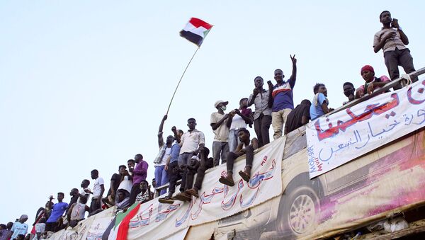 Demonstrators wave their national flag as they attend a protest rally demanding Sudanese President Omar Al-Bashir to step down outside Defence Ministry in Khartoum, Sudan April 10, 2019. - Sputnik Afrique