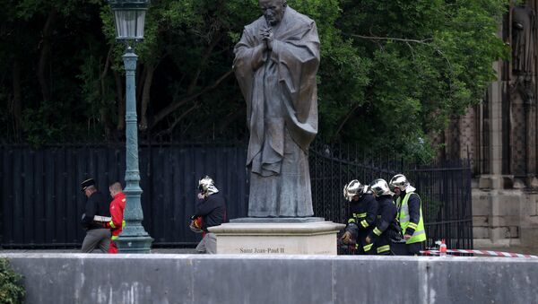 des sapeurs-pompiers près de la sculpture de Jean-Paul II après de l'incendie à Notre Dama de Paris - Sputnik Afrique