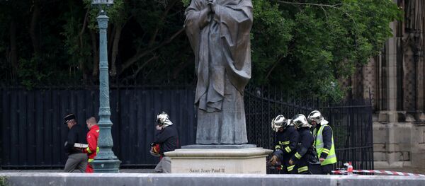 des sapeurs-pompiers près de la sculpture de Jean-Paul II après de l'incendie à Notre Dama de Paris - Sputnik Afrique