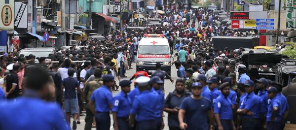 Sri Lankan police officers clear the road as an ambulance drives through carrying injured of Church blasts in Colombo, Sri Lanka, Sunday, April 21, 2019. A Sri Lanka hospital spokesman says several blasts on Easter Sunday have killed dozens of people. - Sputnik Afrique