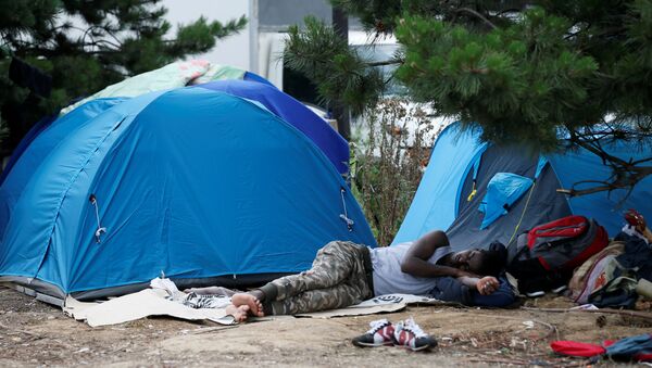 A migrant sleeps next to tents installed in a street near the entrance of the reception center for migrants and refugees at porte de La Chapelle, north of Paris, France, July 6, 2017 - Sputnik Afrique