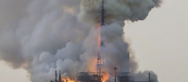 Flames and smoke are seen billowing from the roof at Notre-Dame Cathedral in Paris on April 15, 2019. A fire broke out at the landmark Notre-Dame Cathedral in central Paris, potentially involving renovation works being carried out at the site, the fire service said. - Sputnik Afrique