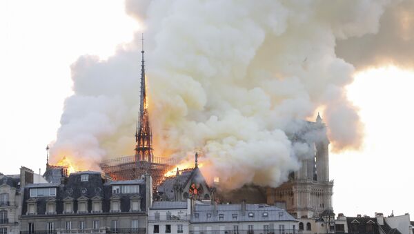 Smoke and flames rise during a fire at the landmark Notre-Dame Cathedral in central Paris on April 15, 2019, potentially involving renovation works being carried out at the site, the fire service said. - Sputnik Afrique