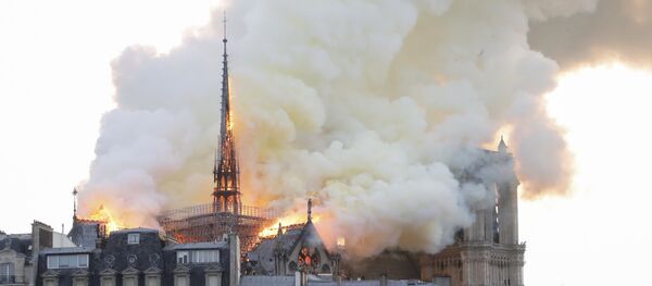 Smoke and flames rise during a fire at the landmark Notre-Dame Cathedral in central Paris on April 15, 2019, potentially involving renovation works being carried out at the site, the fire service said. - Sputnik Afrique