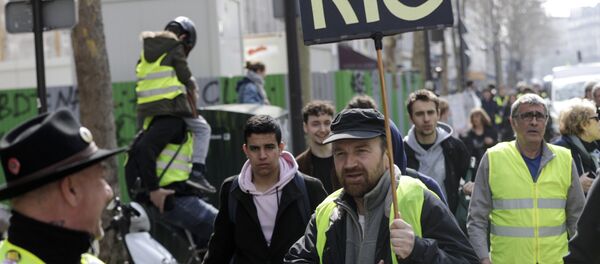 A Yellow Vest protester holds a sign reading RIC (Citizens Initiated Referendum), during an anti-government demonstration called by the 'Yellow Vest' (gilets jaunes) movement in Paris, on March 23, 2019. Demonstrators hit French city streets again on March 23, for a 19th consecutive week of nationwide protest against the French President's policies and his top-down style of governing, high cost of living, government tax reforms and for more social and economic justice. A Yellow Vest protester holds a sign reading RIC (Citizens Initiated Referendum), during an anti-government demonstration called by the 'Yellow Vest' (gilets jaunes) movement in Paris, on March 23, 2019. Demonstrators hit French city streets again on March 23, for a 19th consecutive week of nationwide protest against the French President's policies and his top-down style of governing, high cost of living, government tax reforms and for more social and economic justice. - Sputnik Afrique