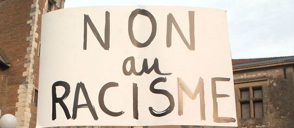 Une manifestante brandit une pancarte proclamant Non au racisme lors d'un rassemblement réunissant près de 500 personnes selon la police, le 08 janvier 2004 à Agen - Sputnik Afrique