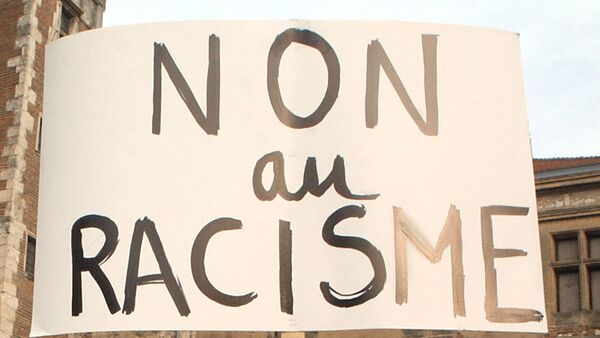 Une manifestante brandit une pancarte proclamant Non au racisme lors d'un rassemblement réunissant près de 500 personnes selon la police, le 08 janvier 2004 à Agen - Sputnik Afrique