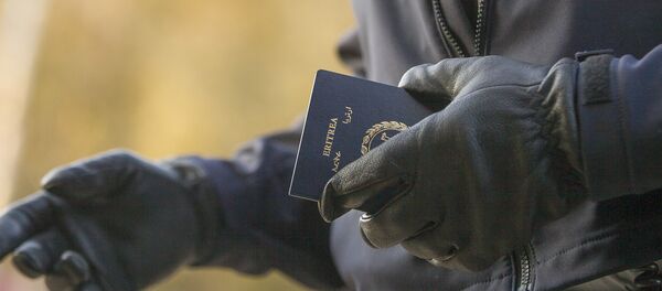 Un officier de la police aux frontières tient le passeport d'une femme érythréenne après son passage illégal de la frontière américano-canadienne (image d'illustration) Un officier de la police aux frontières tient le passeport d'une femme érythréenne après son passage illégal de la frontière américano-canadienne (image d'illustration) - Sputnik Afrique