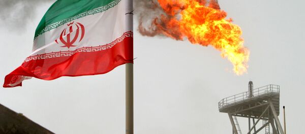 A gas flare on an oil production platform in the Soroush oil fields seen alongside an Iranian flag - Sputnik Afrique
