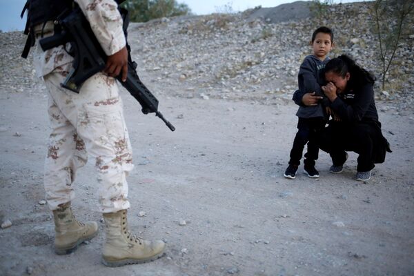 Une femme et un enfant arrêtés par un soldat de la garde nationale du Mexique près de la frontière des États-Unis. - Sputnik Afrique