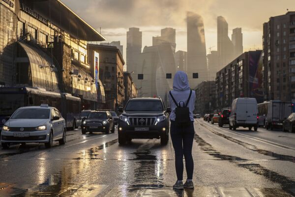 Jeune femme traversant une rue sur fond des gratte-ciel du quartier d’affaires Moscow-City - Sputnik Afrique