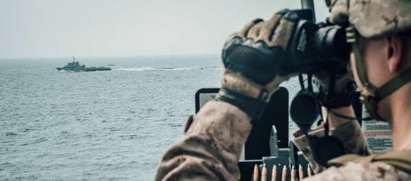 Un militaire américain observe un vaisseau d'attaque rapide iranien du USS John P. Murtha pendant le transit du détroit d'Ormuz, dans la mer d'Oman au large d'Oman Un militaire américain observe un vaisseau d'attaque rapide iranien du USS John P. Murtha pendant le transit du détroit d'Ormuz, dans la mer d'Oman au large d'Oman - Sputnik Afrique