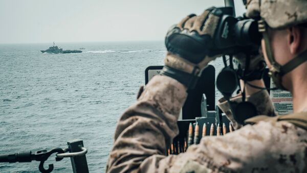 Un militaire américain observe un vaisseau d'attaque rapide iranien du USS John P. Murtha pendant le transit du détroit d'Ormuz, dans la mer d'Oman au large d'Oman - Sputnik Afrique