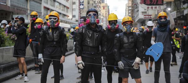 Protesters with protection gears face with riot policemen on a street during the anti-extradition bill protest in Hong Kong, Sunday, Aug. 11, 2019. Police fired tear gas late Sunday afternoon to try to disperse a demonstration in Hong Kong as protesters took over streets in two parts of the Asian financial capital, blocking traffic and setting up another night of likely showdowns with riot police. - Sputnik Afrique