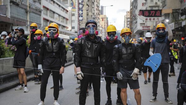 Protesters with protection gears face with riot policemen on a street during the anti-extradition bill protest in Hong Kong, Sunday, Aug. 11, 2019. Police fired tear gas late Sunday afternoon to try to disperse a demonstration in Hong Kong as protesters took over streets in two parts of the Asian financial capital, blocking traffic and setting up another night of likely showdowns with riot police. - Sputnik Afrique