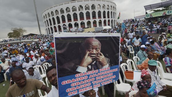 Un homme tient une pancarte montrant une photo de Laurent Gbagbo - Sputnik Afrique