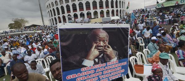 Un homme tient une pancarte montrant une photo de Laurent Gbagbo - Sputnik Afrique