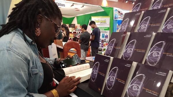 Une lectrice feuilletant le livre de Lamazone Wassawaney à l’édition 2019 du SILA à Abidjan  - Sputnik Afrique