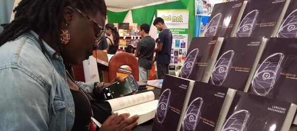 Une lectrice feuilletant le livre de Lamazone Wassawaney à l’édition 2019 du SILA à Abidjan Une lectrice feuilletant le livre de Lamazone Wassawaney à l’édition 2019 du SILA à Abidjan - Sputnik Afrique