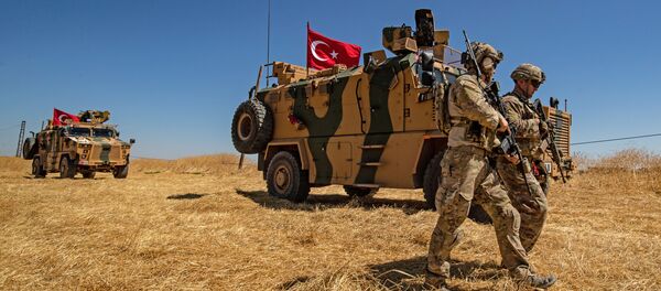 (FILES) In this file photo taken on September 08, 2019 US troops walk past a Turkish military vehicle during a joint patrol with Turkish troops in the Syrian village of al-Hashisha on the outskirts of Tal Abyad town along the border with Turkish troops - Sputnik Afrique