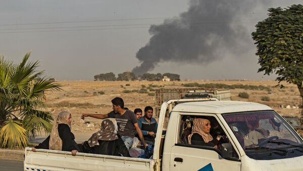 Civilians ride a pickup truck as smoke billows following Turkish bombardment on Syria's northeastern town of Ras al-Ain in the Hasakeh province along the Turkish border on October 9, 2019 - Sputnik Afrique