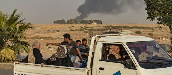 Civilians ride a pickup truck as smoke billows following Turkish bombardment on Syria's northeastern town of Ras al-Ain in the Hasakeh province along the Turkish border on October 9, 2019 - Sputnik Afrique