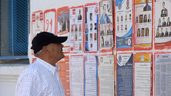 Un Tunisien devant les affiches des différents candidats aux législatives tunisiennes - Sputnik Afrique